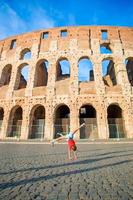 Adorable little active girl having fun in front of colosseum in Rome, Italy. Cute sporty kid making wheel background of famous attractive in Europe. photo