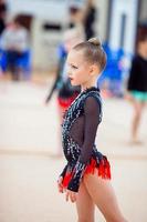 hermosa pequeña gimnasta entrenando en la alfombra y lista para las competiciones foto