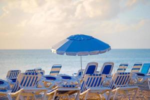 Public beach in a popular resort in the Caribbean with umbrellas and chaise-lounges photo