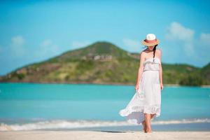 Young beautiful woman on tropical seashore. Happy girl relaxing at white sand tropical beach photo