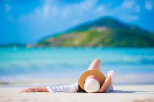 Young woman enjoying the sun sunbathing by perfect turquoise ocean. photo