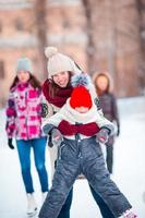 niña adorable con su madre patinando en la pista de hielo foto