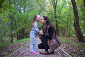 Cute little girl kissing her mother's nose photo