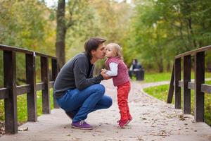 Father kissing his little daughter in a park photo