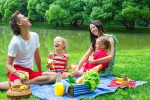 familia feliz haciendo un picnic en el parque y diviértete foto