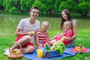 Happy young family picnicking outdoors near the lake photo