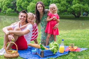 feliz linda familia de cuatro personas haciendo un picnic al aire libre foto