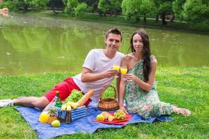 joven pareja feliz haciendo un picnic al aire libre cerca del lago foto