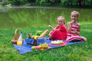 Cute little girls picnicing in the park at sunny day photo