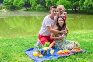 feliz linda familia de tres personas haciendo un picnic al aire libre foto