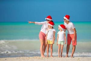 Happy family with two kids in Santa Hat on summer vacation photo