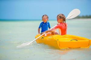 Little adorable girls enjoying kayaking on yellow kayak photo