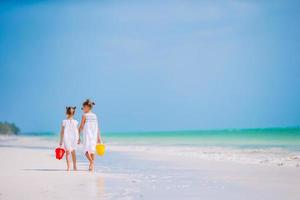 Little happy funny girls have a lot of fun at tropical beach playing together. Sunny day with rain in the sea photo