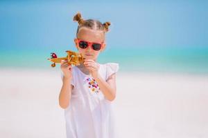 niña feliz jugando con un avión de juguete en la playa. niño sueña con convertirse en piloto foto