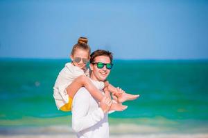 Little girl and happy dad having fun during beach vacation photo