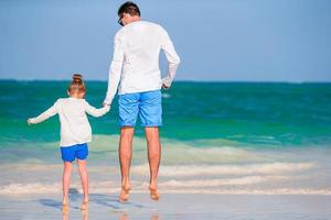 Little girl and happy dad having fun during beach vacation photo