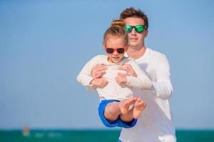 Little girl and happy dad having fun during beach vacation photo