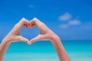 Closeup of heart made by hands background turquoise water photo