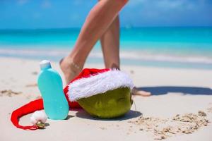 crema solar y sombrero de santa en coco en la playa exótica blanca foto