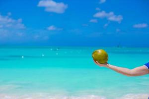 Closeup of coconut in hands against the turquoise sea photo