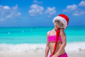 Little adorable girl in red Santa Hat on tropical beach photo