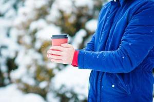 Closeup coffee to go in male hands at frozen winter day outdoors photo