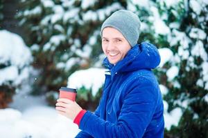 joven caucásico bebiendo café caliente en un día de invierno congelado al aire libre