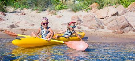 niñas lindas disfrutando del kayak en kayak amarillo en el agua turquesa clara foto