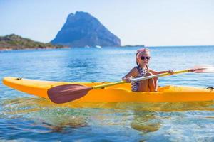 pequeña niña valiente y linda haciendo kayak en el mar azul claro foto