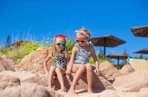 Adorable cute girls have fun on white beach during vacation photo