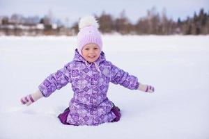 niña feliz divirtiéndose en la nieve en el día soleado de invierno foto