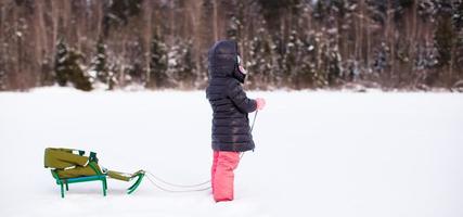 niña linda ir en trineo en un cálido día de invierno foto