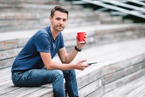 Man is reading text message on mobile phone while walking in the park photo