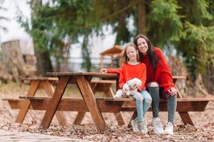 Mother and daughter playing with dog outdoors photo