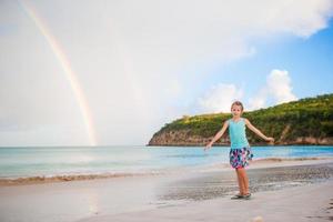 Happy little girl backgound the beautiful rainbow over the sea. Beautiful rainbow on caribbean beach photo