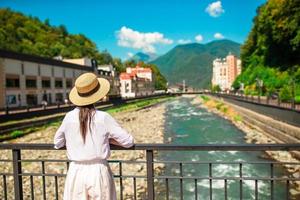 chica feliz con sombrero en el terraplén de un río de montaña en una ciudad europea. foto