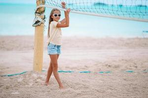 Little adorable girl playing voleyball on beach with ball. photo