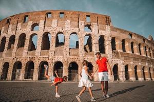 familia feliz en europa. padres e hijos en roma sobre el fondo del coliseo foto