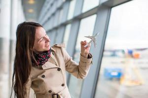 mujer feliz con avión modelo pequeño dentro del aeropuerto foto