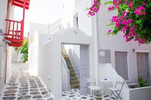 The narrow streets with blue balconies, stairs, white houses and flowers in beautiful village in Greece. Beautiful architecture building exterior with cycladic style in Mykonos photo