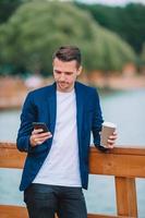 Happy young urban man working and drinking coffee in european city outdoors photo