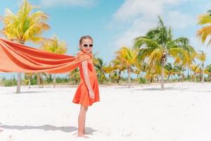 niña pequeña jugando al superhéroe en una playa tropical foto