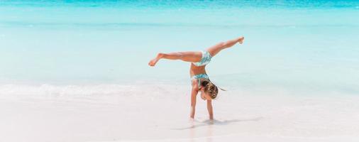 Adorable active little girl at beach during summer vacation photo