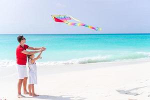 Family flying kite together at tropical white beach photo