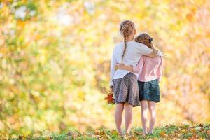 Little adorable girls at warm day in autumn park outdoors photo