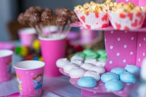 Sweet colored meringues, popcorn, custard cakes and cake pops on table photo