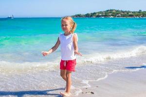 Adorable little girl playing in shallow water at white beach photo