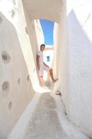 Young man walking in narrow streets of Emporio village on the island Santorini,Greece photo