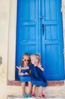 niñas adorables sentadas cerca de la antigua puerta azul en el pueblo griego de emporio, santorini