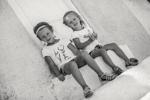 Little cute sisters sitting near old house in Greek village of Emporio, Santorini photo